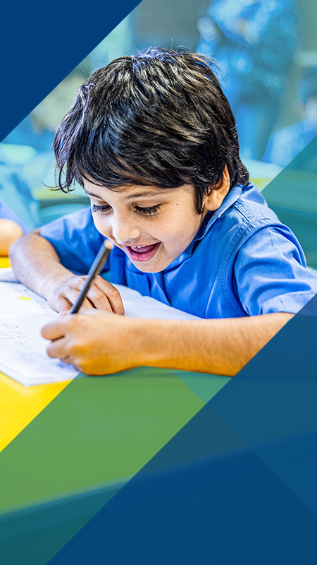 Student writing at his desk in the classroom at Our Lady of Lourdes Primary School Baulkham Hills South