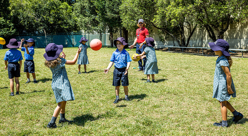 Students throwing the ball to each other in the playground at Our Lady of Lourdes Primary School Baulkham Hills South